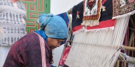 Woman making a carpet on a hand loom.